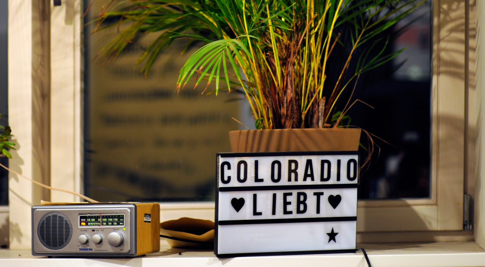 Ein Radio und unser Schild "Coloradio liebt"