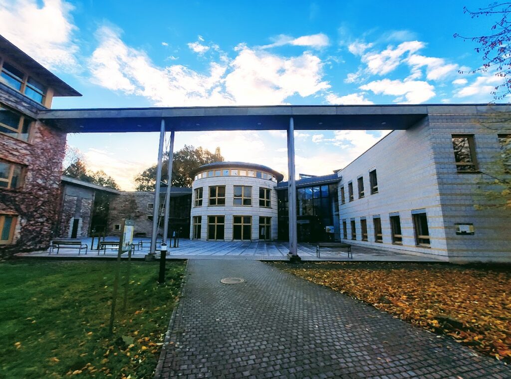 Das Bild zeigt mehrere flache Gebäude die über ein kleines Vordach verbunden sind.