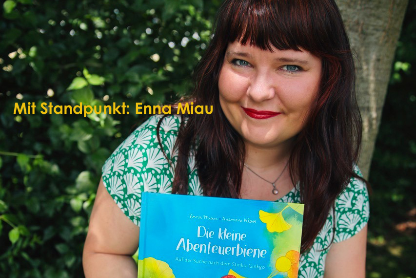 Eine Frau hält ein das Buch: Die kleine Abenteuerbiene. Auf dem Bild steht: Mit Standpunkt: Enna Miau.