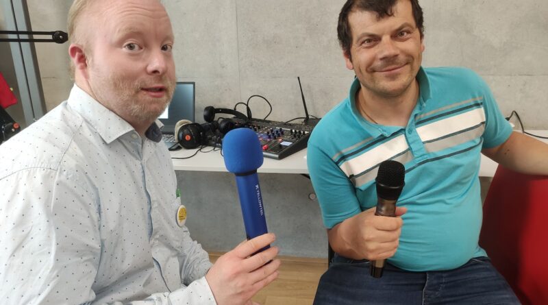 Das Bild zeigt zwei Männer die beide ein Mikrophon in der Hand halten.
