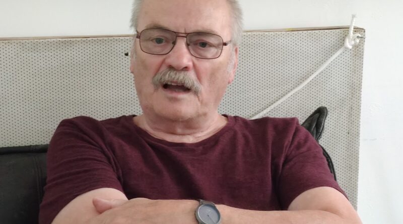 Das Bild zeigt einen älteren Herren der die Arme vor der Brust verschränkt hat.