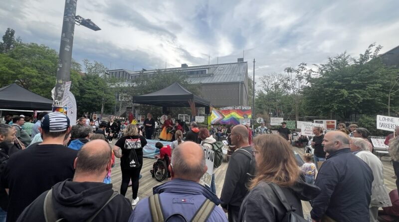 Viele Menschen stehen auf einem Platz. Einige von ihnen halten Banner hoch. Auf den steht: Gleichberechtigung für alle und Menschenrechte sind nicht verhandelbar. In der Mitte steht ein Pavillon, dort spricht Manuel Schramm.